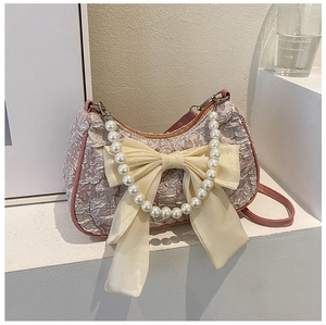 Dettaglio della borsa a pieghe lilla con manico di perle e un grande fiocco in chiffon