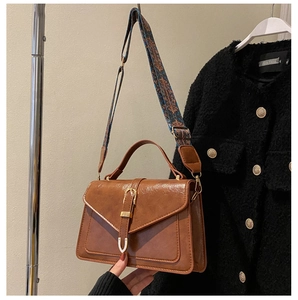 Detail of vintage brown PU leather handbag featuring a chic gold buckle and woven strap