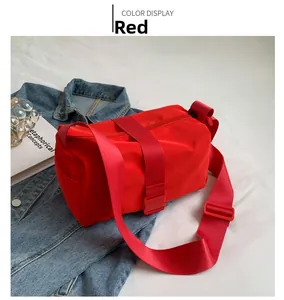 Detail view of red cylindrical Oxford cloth crossbody bag with adjustable wide strap