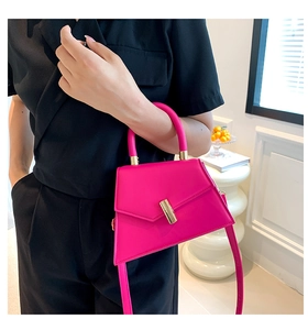 Detail of rose pink mini handbag with gold metal clasp and adjustable shoulder strap