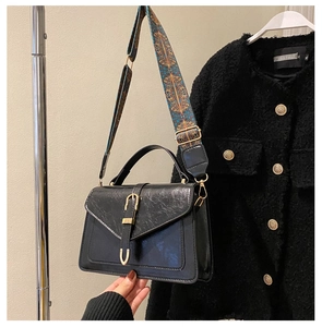 Detail of vintage black crossbody bag with textured leather and ethnic woven strap