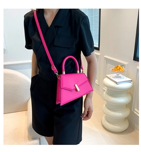 Detail of a bright pink trapezoid leather bag with gold metal lock and round handle