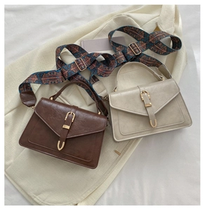 Detail view of brown and beige crossbody bags with geometric ethnic patterned wide straps