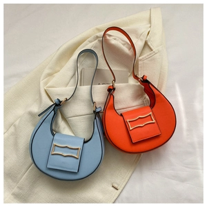 Close-up of light blue and orange stone-textured underarm bags with gold geometric hardware