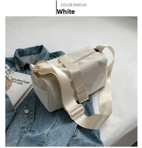 Detail of white nylon crossbody bag featuring a wide strap resting on denim jacket