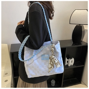 Detail of light blue checkered tote bag featuring woven straps and decorative silk scarf