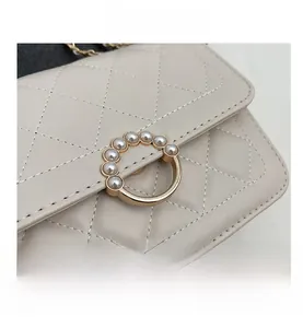 Detail of quilted beige leather bag with gold ring closure and pearl decorations