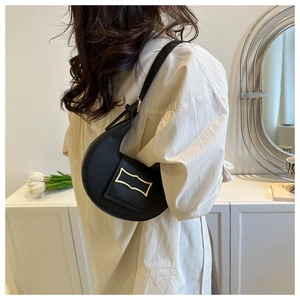 Detail of black crescent shoulder bag featuring premium stone texture and gold hardware