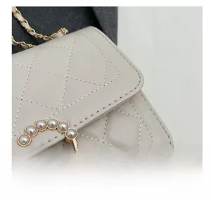 Close-up of quilted cream faux leather with pearl-embellished gold round buckle details