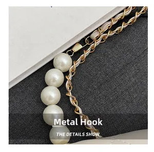 Detail of elegant pearl strap and gold metal chain with hardware hook on a stylish handbag