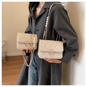 Detailed view of quilted faux leather bag with elegant pearl strap and round pearl lock