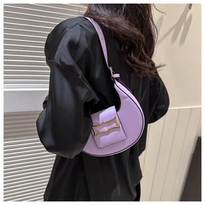 Detail view of purple crescent shoulder bag with golden buckle on black satin blouse