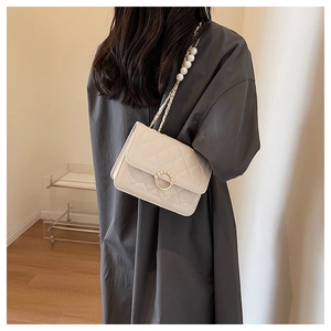 Detail of cream quilted crossbody bag with decorative pearl strap and pearl ring clasp