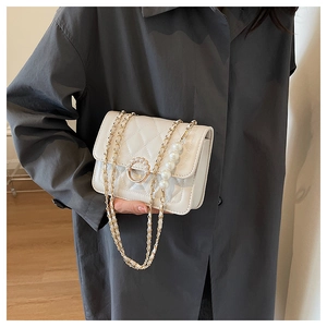 Close-up of a white quilted mini bag with pearl buckle and decorative pearl chain