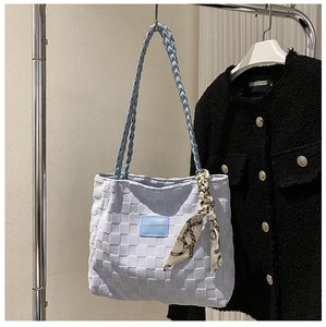 Detail of light blue textured tote bag with woven strap and decorative silk scarf