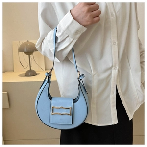 Detail of light blue crescent bag with gold metal buckle and sleek black edge paint finish