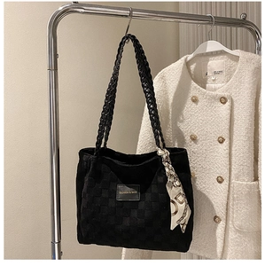Detail of black tote bag with checkered texture and elegant scarf on a silver hanger