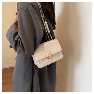 Close-up of white quilted mini flap bag with pearl chain strap and ring clasp detail