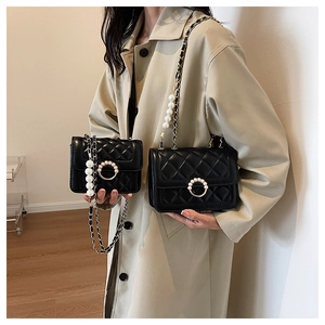 Detail of black quilted flap bags in two sizes with pearl buckles and chain straps