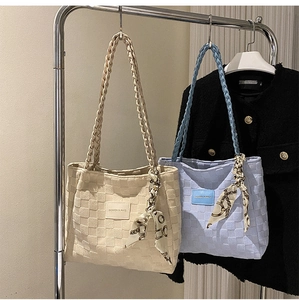 Detail of checkered embossed tote bag with braided handles and decorative silk scarf