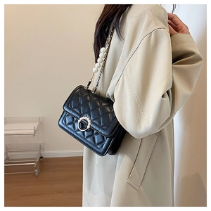 Detail of black quilted shoulder bag with pearl-inlaid metal buckle and chain strap