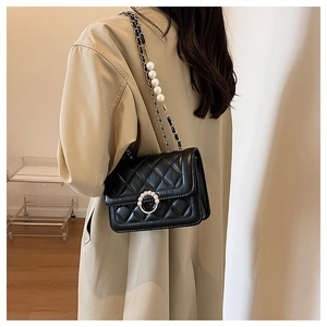Detail of black quilted leather shoulder bag with pearl chain and elegant lock decoration