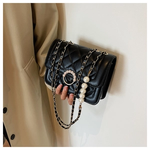 Detail of black quilted leather mini bag featuring pearl buckle and chain strap