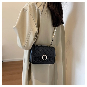 Detail of black quilted leather mini bag featuring elegant pearl chain and round buckle