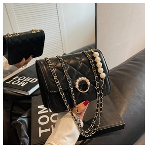 Detail of black quilted leather mini bag with gold chain and luxury pearl accents