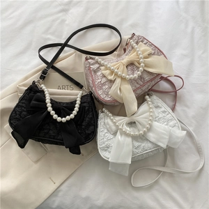 Tre eleganti mini borse con manici di perle e grandi fiocchi in nero, rosa e bianco