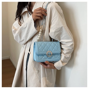 Close-up of light blue quilted crossbody bag with pearl chain strap and gold hardware