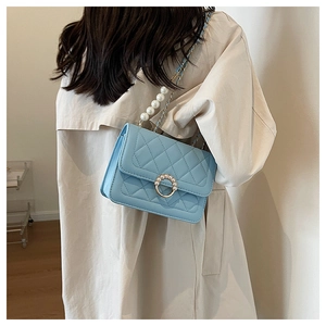 Detail of light blue quilted leather bag featuring elegant pearl buckle and chain strap