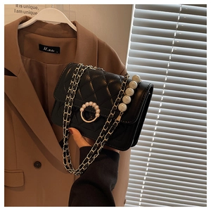 Close-up of black quilted mini bag with elegant pearl clasp and chain shoulder strap