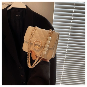 Detail of quilted white mini bag featuring large pearl chain and gold metal clasp