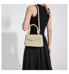 Detail of beige straw woven shoulder bag with envelope flap and textured handle