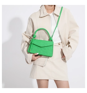 Close-up of bright green woven texture handbag with chunky handle on minimalist model