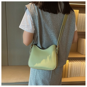 Close-up of a light green crescent shoulder bag with smooth leather finish and strap