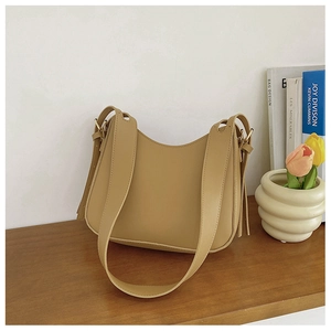 Detail of camel brown faux leather crescent bag with fringe tassels and wide shoulder strap