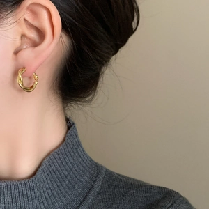 Elegant gold twisted hoop earrings for women with a polished texture shown on a model