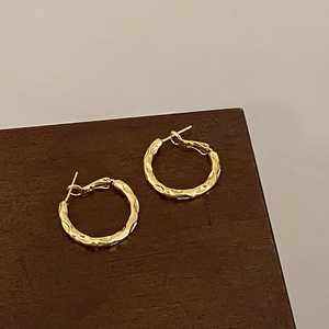 Detail of gold hammered hoop earrings featuring textured surface and secure clasp