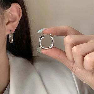 Gros plan de boucles d'oreilles créoles carrées en argent avec une finition métallique lisse