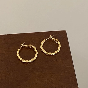 Detailed view of gold plated hoop earrings with unique hammered crushed silver texture