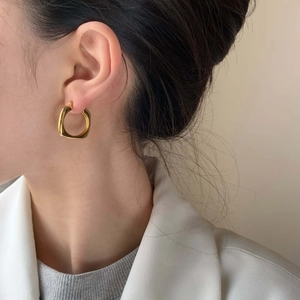 Gros plan sur la boucle d'oreille carrée dorée minimaliste avec finition miroir polie