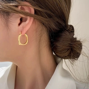 Elegant gold square geometric earrings with minimalist glossy metal finish on a model