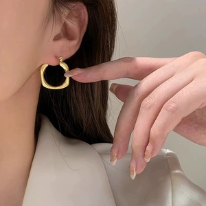 Minimalist gold irregular geometric earrings with high polish finish worn by a model