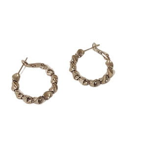 Boucles d'oreilles créoles torsadées géométriques dorées avec texture sur fond blanc