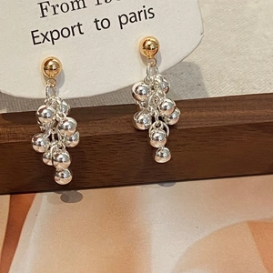Dettaglio di orecchini bicolore con perle di metallo a grappolo oro e argento lucido