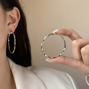 Chic silver geometric spiral twist hoop earrings shown on model in white blazer
