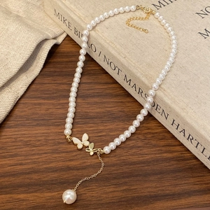 Detail of French vintage pearl necklace with gold butterfly charms on a rustic wood surface