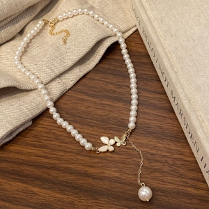Detail of vintage butterfly pendant with white pearl tassel on gold necklace chain